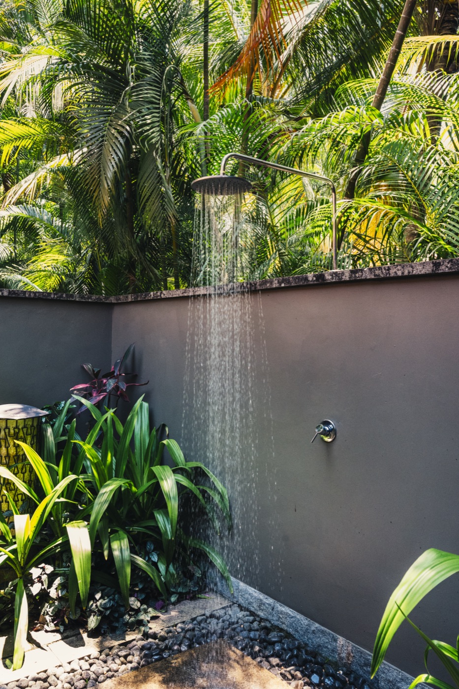 Open-air shower walled in stone and palms